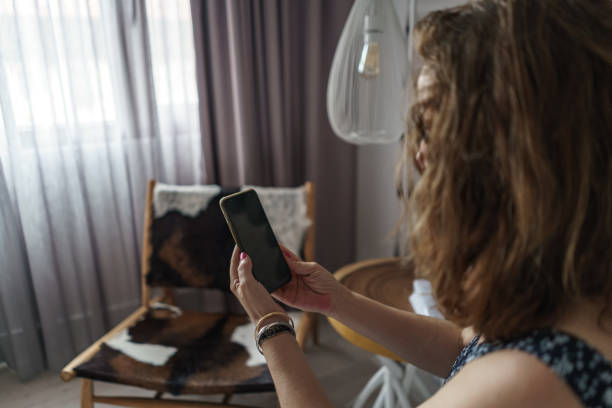 istock Woman from behind looking at mobile phone while resting in her room during the day. 1324237644