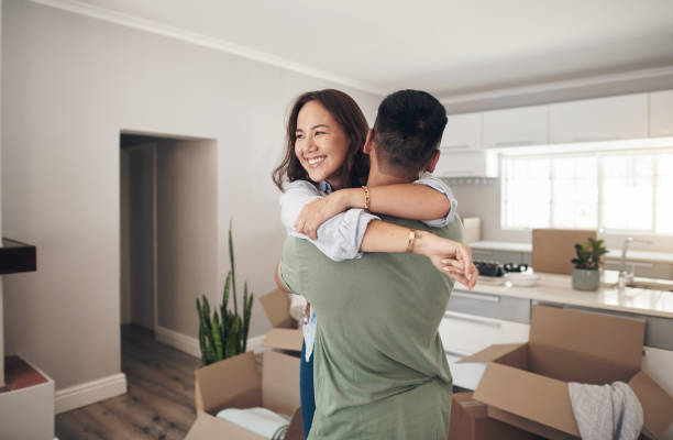 Shot of a couple looking cheerful while moving into their new home We did it! We bought our first home! home ownership stock pictures, royalty-free photos & images