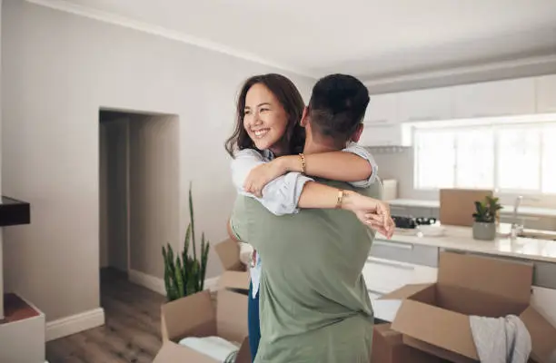 Photo of Shot of a couple looking cheerful while moving into their new home