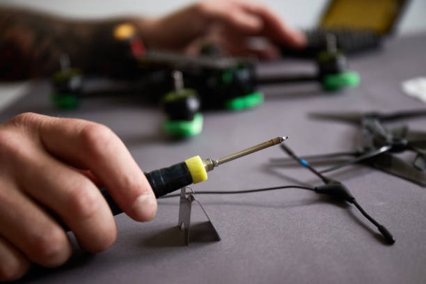 istock Close up of man's hands assembling a drone from parts, using tools, Preparing high-speed racing quadcopter for flight. Repair drone before training process. 1324238562