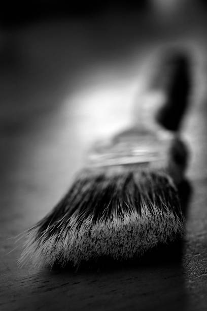 Two brushes for painting on a yellow background with artificial light.