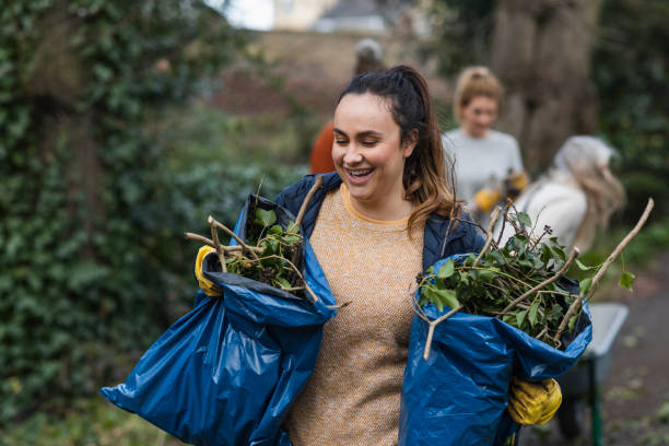 Zero Waste Gardening A front view of a young brunette woman carrying two bags of garden waste that is to be composted and reused. She is working on a community space garden in Hexham in the North East of England with a group of friends. resourceful stock pictures, royalty-free photos & images