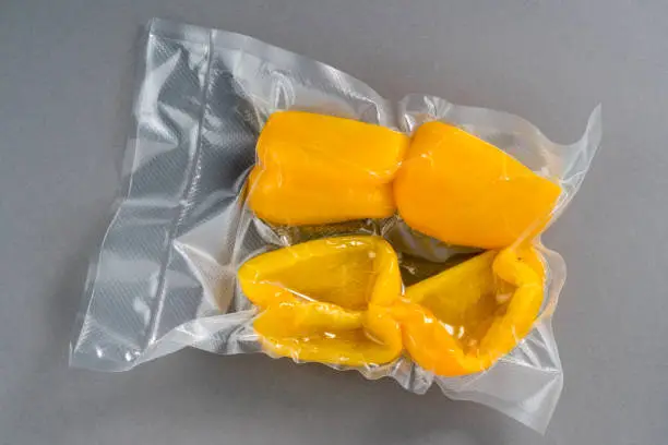 yellow peppers in vacuum packed sealed for sous vide cooking, isolated on grey background
