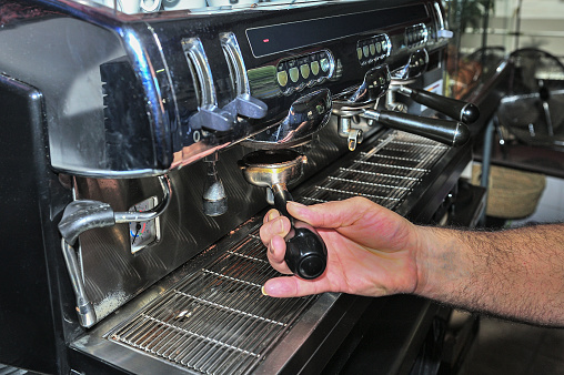 Waiter makes a good coffee in expresso machine