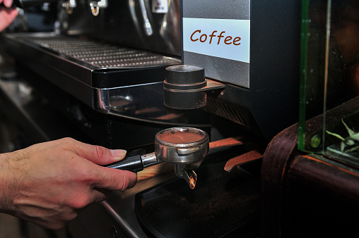 Waiter makes a good coffee in expresso machine
