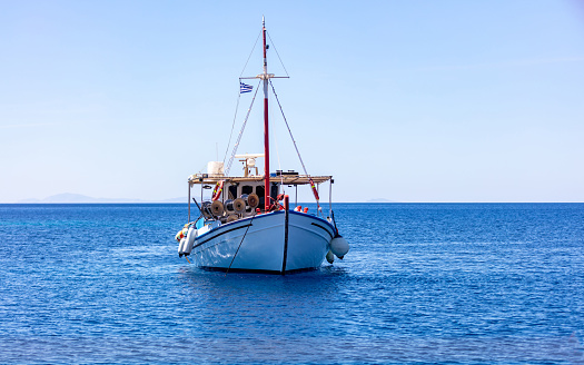 Fishing boat colorful moored at open sea, Ios island Cyclades, Greece.