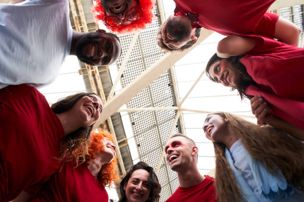istock View from below of a group of people celebrating together and hugging while cheering for their sports team from a stadium. Cheerful fans watch the game in costume at the stadium. 1324257805