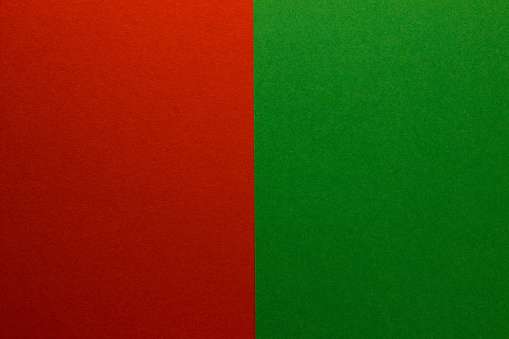 Background of two vertical rectangles red and green. Sheets of blank red and green paper with fine texture, split vertically.
