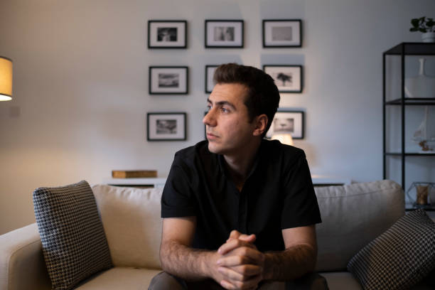 istock Man sitting alone at home looking sad and distraught 1324264633