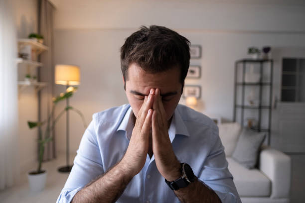 istock Man sitting alone at home looking sad and distraught 1324264685