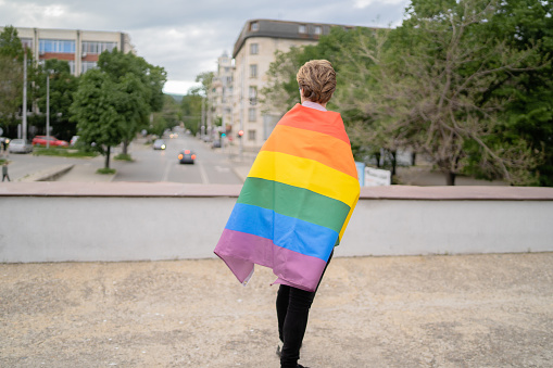 Young gay man, covered with the rainbow flag