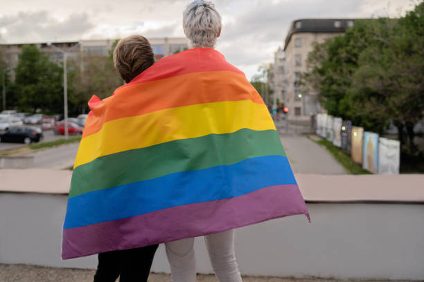 街を見て虹の旗を持つ素敵な男性カップル - two flags ストックフォトと画像