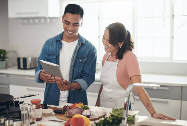 istock Shot of a young couple using a digital tablet while cooking together at home 1324273752