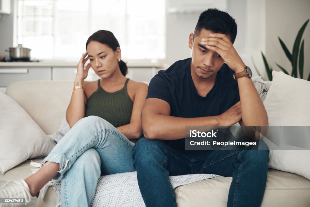 Shot of a young couple ignoring each other after an argument at home This is a tough issue to deal with Couple - Relationship Stock Photo
