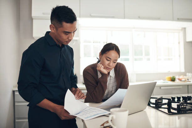 istock Shot of a young couple going through paperwork while using a laptop at home 1324274546