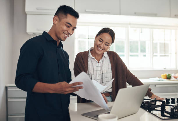 istock Shot of a young couple going through paperwork while using a laptop at home 1324274548