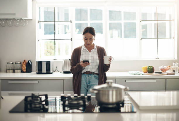 istock Shot of a young woman using a cellphone while drinking coffee in the kitchen at home 1324275734