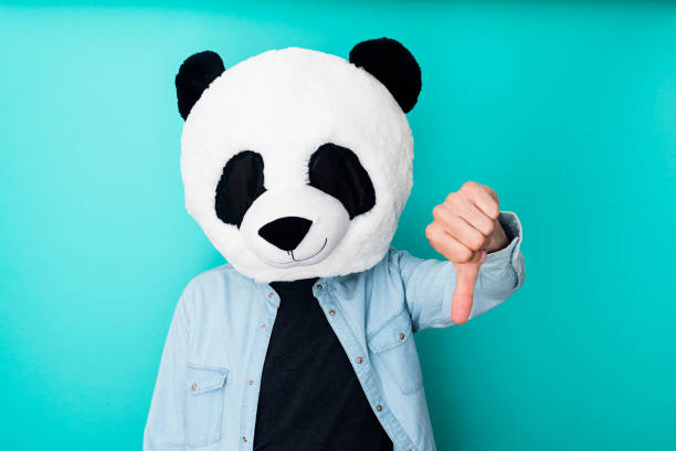 istock Man in panda mask with thumbs down gesture. Showing rejection and negative concept 1324275852