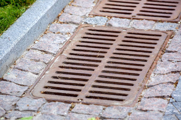 istock iron rusty hatch rectangular grating of the drainage system of the pedestrian sidewalk made of rough cut stone tiles near the granite curb close-up view, nobody. 1324280386