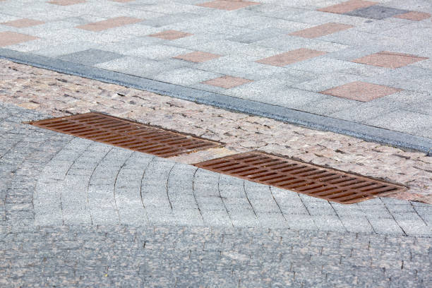 istock 2 rusty iron hatch rectangular grating of the drainage system on the road with paved stone tiles near the pedestrian sidewalk made of granite close-up view, nobody. 1324280388