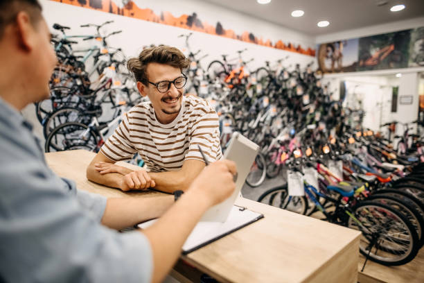 I decided which bike to buy A man is buying a bicycle in a bicycle shop bicycle shop stock pictures, royalty-free photos & images