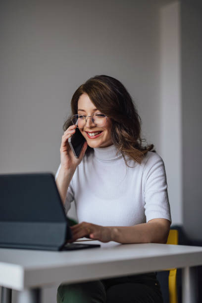 istock Work At Home: Young Businesswoman Holding  A Mobile And Looking At Computer 1324283182