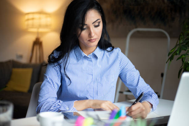 istock Businesswoman sitting at desk makes notes writing on notepad stock photo 1324284802
