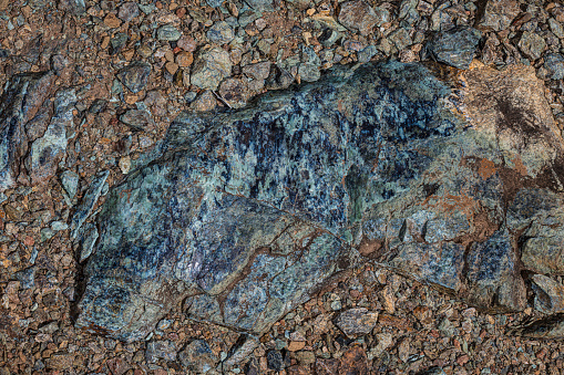 Serpentinite or serpentine is a rock composed of one or more of the serpentine group of common rock-forming hydrous magnesium iron phyllosilicate minerals; they may contain minor amounts of  chromium, manganese, cobalt and nickel. Minerals in this group, which are rich in magnesium and water, light to dark green, greasy looking and slippery feeling, are formed by serpentinization. Modini Mayacamas Preserve.