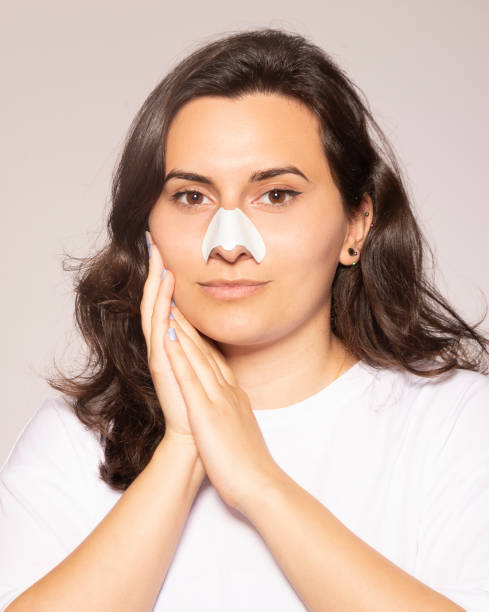 istock Young beautiful woman is using nose strip for blackheads. 1324286365