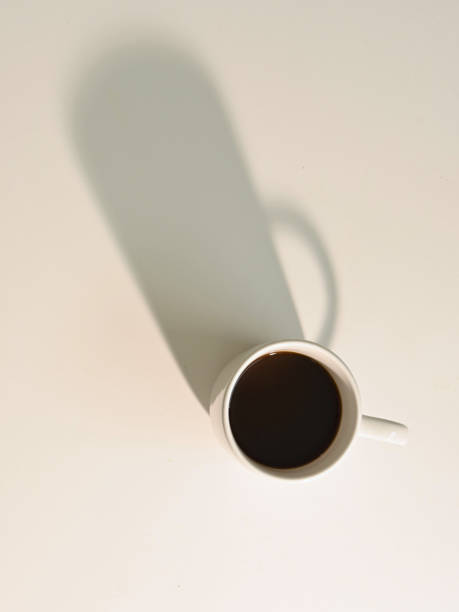 istock Overhead shot of white cup with coffee with strong shadows, light background and copy space 1324288403