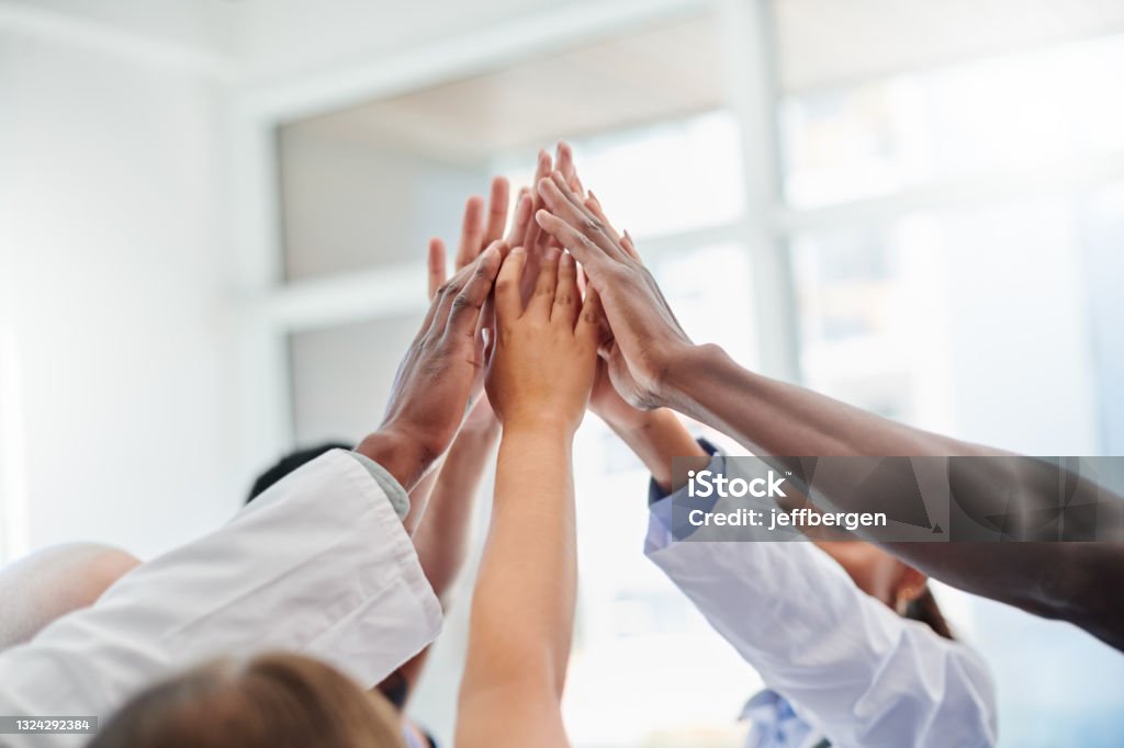 Shot of a set of hands high fiving in victory Here to motivate each other Teamwork Stock Photo