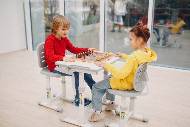 istock Little kids playing chess at kindergarten or elementary school 1324294939