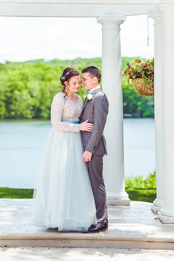 Bride and groom stand together outdoors on their wedding day