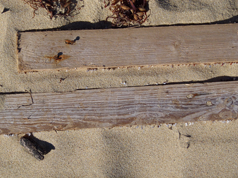 Old timber boards  abandoned on a beach with rusty nails