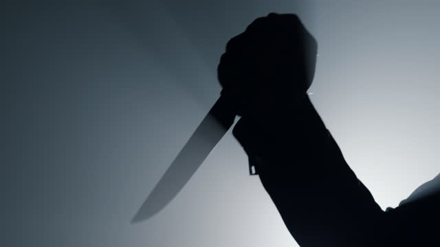 Silhouette man arm holding knife in dark. Criminal hand attacking with dagger.