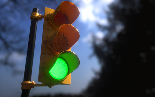 Outdoor Vertical Traffic Light Green Color Outdoor vertical traffic light with blue sky and trees around. Traffic control concept image with shallow depth of field. blue yellow lights stock pictures, royalty-free photos & images