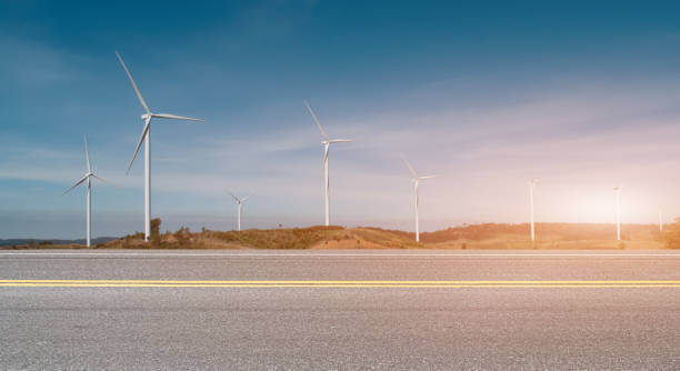 istock Asphalt road with wind turbines at sunset background 1324310000