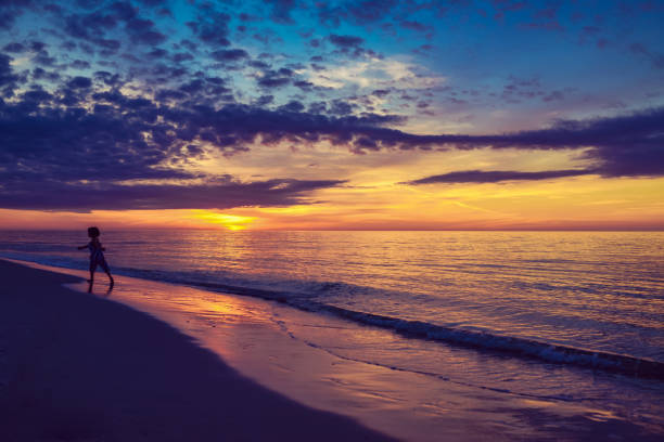 istock Child in silhouette on a scenic idyllic beach at sunset 1324312734