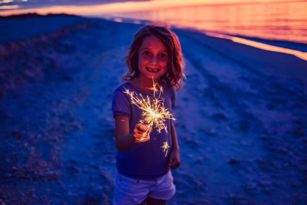 istock Child with a firework sparkler on a stunning idyllic beach at sunset, joy and freedom in childhood 1324312875