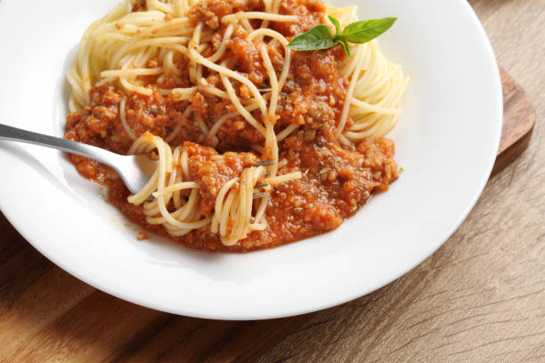 istock Close up a fork with spaghetti and red sauce in white dish on wooden cutting board 1324314904