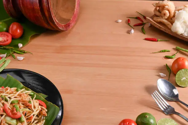 Photo of Papaya salad, ingredients and mortar on wooden background. Thai food concept.