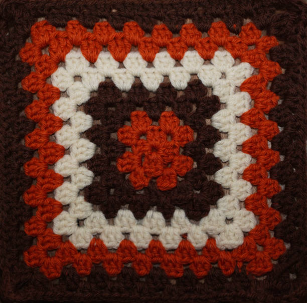 istock Knitted  brown, orange and white squares as background. Pattern for patchwork, quilt. Home decor concept. 1324322587