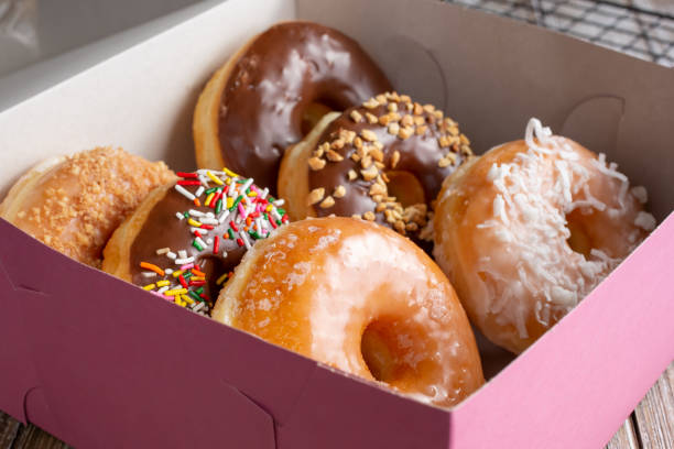 pink box, donuts A view of a pink box filled with a half dozen favorite donut varieties. doughnut stock pictures, royalty-free photos & images