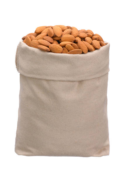 mandorle sano delizioso in una borsa piena su uno sfondo bianco isolato - peanut bag nut sack foto e immagini stock