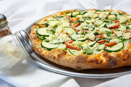 A view of a veggie pizza pie, in a restaurant or kitchen setting.