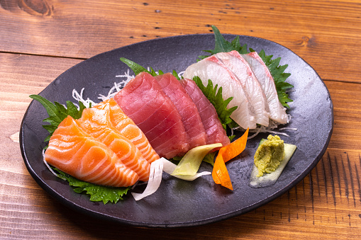 Set of various kinds and types of Japanese food sushi fish ready to eat on a wooden tray on a white background.