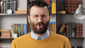 Man disgust, abomination, FU, auch emotion. Bearded male teacher or businessman with glasses looking at camera and his face is distorted in disgust