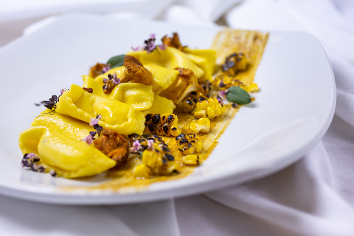 A view of a plate of agnolotti pasta, in a restaurant or kitchen setting.