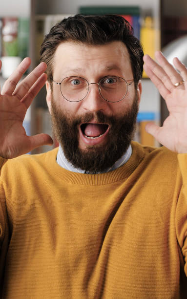 istock Man is scared, terrified. Frightened handsome bearded man in glasses with suddenly throws his hands up and looking at camera, he is very scared and just terrified. Close-up 1324333275