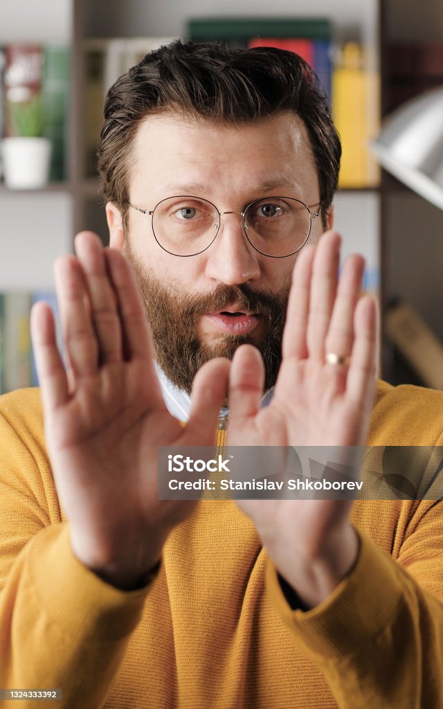 Disagreement, stop, NO says. Frightened worried handsome bearded man in glasses looks at camera and starts waving his arms nervously, shouting no-no-no. Close-up Disagreement, stop, NO says. Frightened worried handsome bearded man in glasses looks at camera and starts waving his arms nervously, shouting no-no-no. Close-up view Adult Stock Photo
